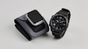 Montre connectée équipée d’un bracelet gonflable pour mesurer la tension, placée à côté d’une montre sportive GPS sur un fond neutre.